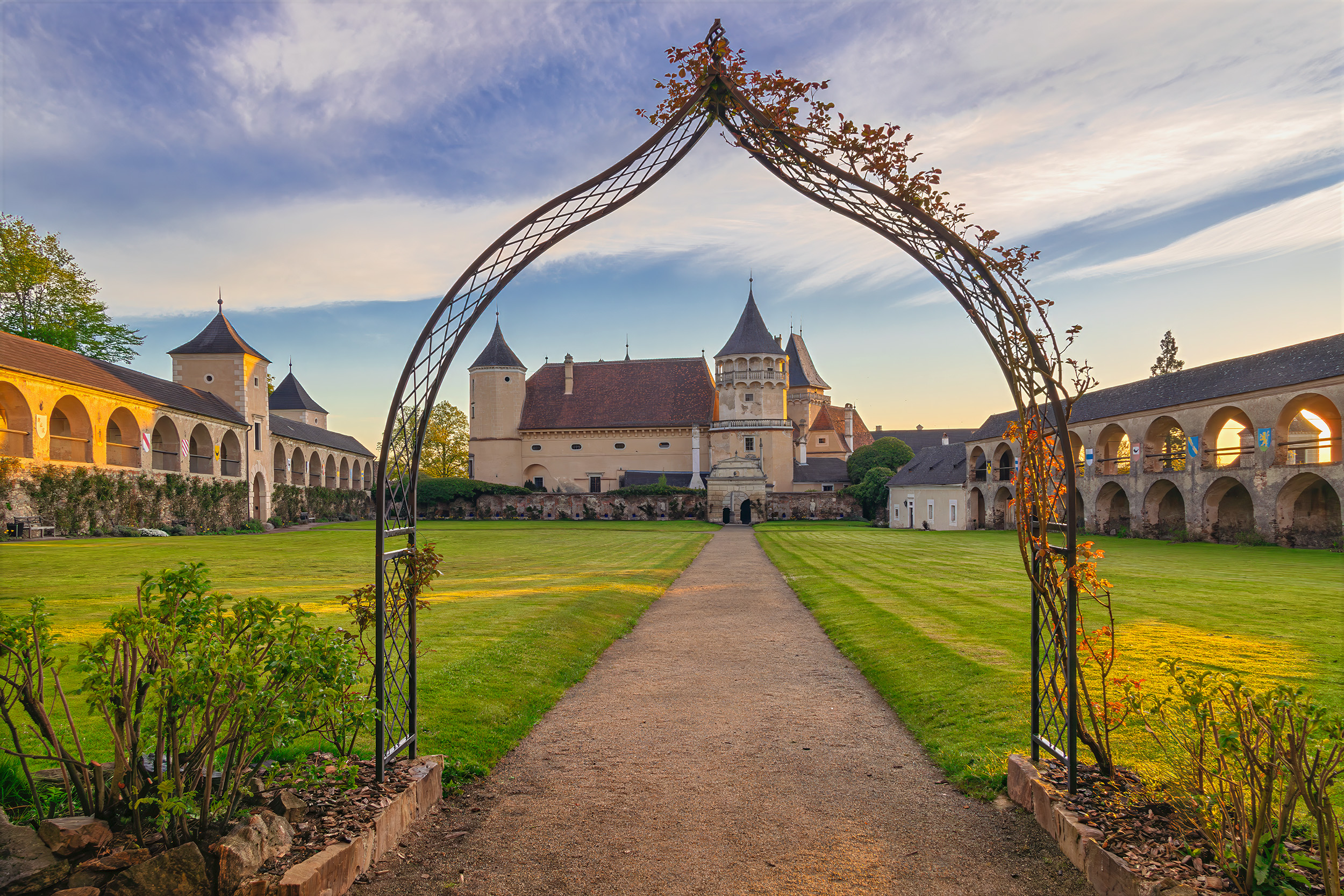 Sunrise at Rosenburg Castle Iconic sunrise view of the historic Rosenburg Castle grounds framed by an ornate metal garden arch at Rosenburg Castle, Austria.