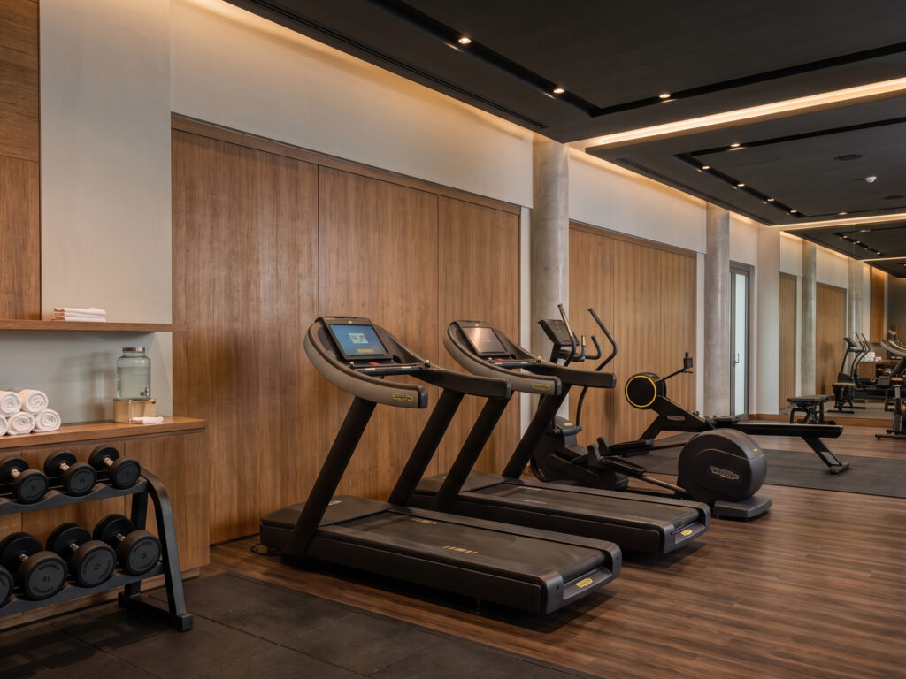 Hotel Fitness Center Aligned treadmills and a neatly racked dumbbell set in a modern hotel fitness center with wood paneling